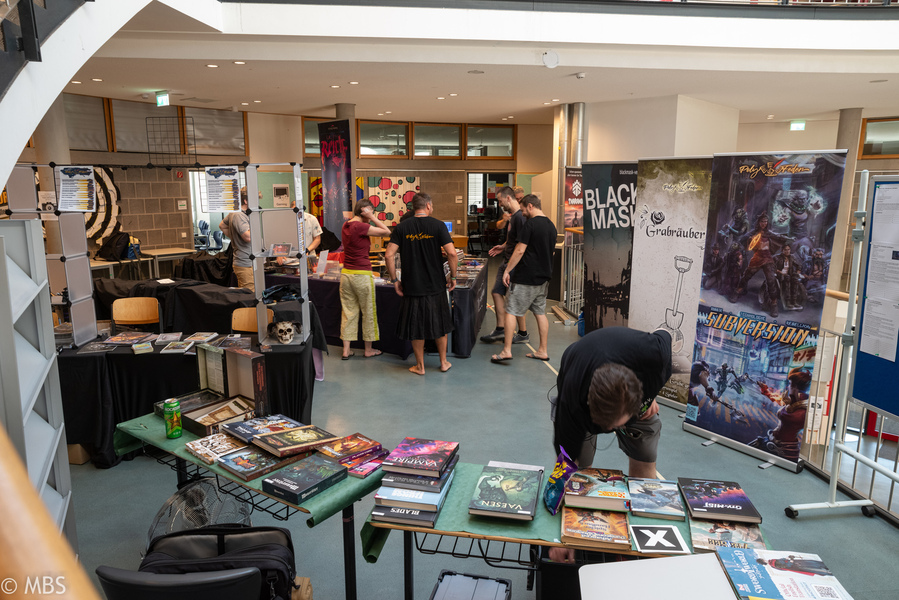Besucher:innen stehen an Ständen voller Rollenspielbücher.