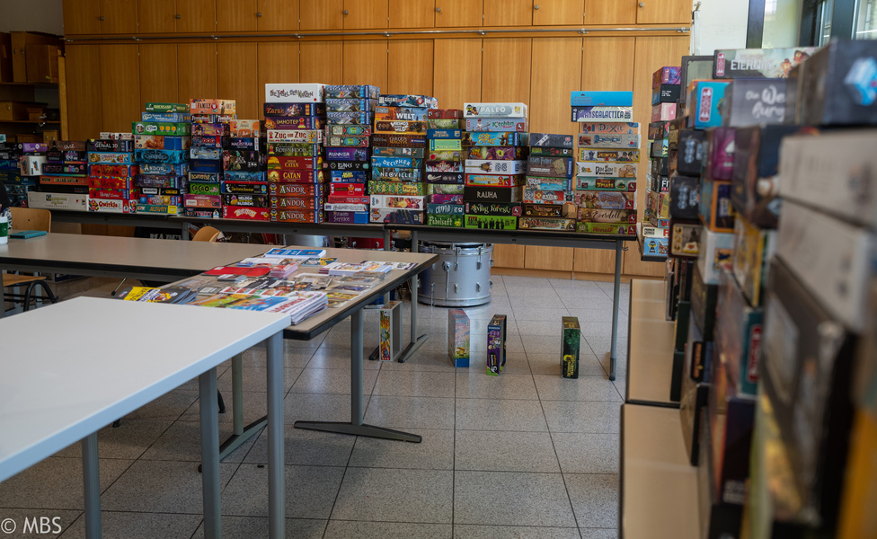 Eine Wand aus Brettspielen hinter dem Stand der Brettspielausleihe.